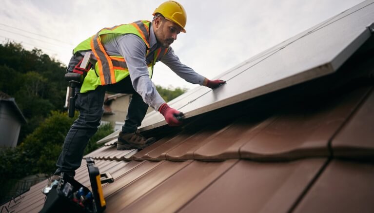 Low angle view of professional worker covering roof with solar panels. Copy space.